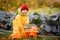 A child in yellow overalls drives a toy car with vegetables against the backdrop of a vegetable garden and cabbage beds