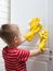 Child in yellow rubber gloves is cleaning. the child wipes the furniture from dust and dirt. Step 2