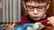 Child young home repairman theme. Cute caucasian preschooler in glasses with a tool repairs a home electronic appliance. Little pr