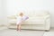 Childhood, babyhood and people concept - happy little baby girl playing near couch at home