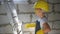 Childhood, construction, architecture, building and people concept - smiling little girl in protective yellow helmet and