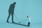 Childhood and dream about big and famous future. Conceptual image with boy and shadow of male golf player on blue