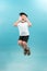 Childhood, expressions and people concept - portrait of smiling boy jumping over light background