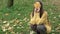 Childhood, family, autumn concept - young beautiful cute girl with long loose dark hair in orange sweater sit on grass