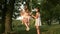 Childhood and family concept. Mom shakes her daughters on a swing under tree in sun, playing with children. mother and