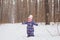 Childhood and people concept - child girl walking in the winter outdoors and throwing the snow up