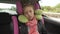 Childhood road trip and people concept - teen girl sleeping in baby car seat with travel pillow