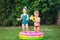 Childhood summer games with water pool. Caucasian brother and sister play with plastic toys watering can pouring water splashing,