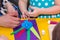 Children and adults hands glue colored paper on application mast