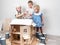 Children as adults: A boy and a girl paint a doll house white and get dirty with paint. Authentic photo.