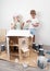 Children as adults: A boy and a girl paint a doll house white and get dirty with paint. Authentic photo.