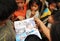 Children of the Ban Huay Daue village are looking at new schoolbooks and a report about war victims due to land mines