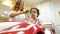 Children barbershop. Little boy sitting in toy car and stylist combs his hair