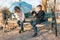 Children best friends boy and girl sitting on a bench in the park with dog dachshund, children talking and smiling, sunny autumn