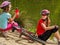 Children bicycle have rest near water in park outdoor.