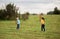 Children - a boy in a blue T-shirt and a girl in yellow play tennis with rackets and a ball on nature