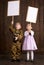 Children boy are dressed as soldier in retro military uniforms and girl in pink dress. They`re holding blank posters for veterans