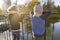 Children boy and girl standing backs on bridge, looking at ducks