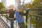 Children boy and girl standing backs on bridge, looking at ducks