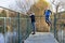 Children boy and girl standing on bridge, looking at ducks