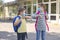 Children, a boy and a girl, wearing masks, greet their elbows on the street in the schoolyard due to the coronavirus epidemic.