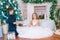 Children, a boy and a girl in a white ball gown near a Christmas tree in holiday dresses with gifts and silver confetti.