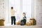 Children brother and sister of preschool age sit by window on a sunny Christmas day and play with gifts boxes wrapped in paper.The