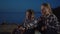 Children camping on beach, sitting by the campfire roasting sausages on a spring evening