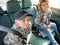 Children in the car. A boy and a girl are sitting in the back seat, laughing and grimacing. Children fasten their seat belts