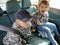 Children in the car. A boy and a girl are sitting in the back seat, laughing and grimacing. Children fasten their seat belts