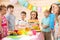 Children celebrating birthday party. Kids stand arround festive table