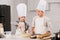 children in chef hats and aprons whisking eggs in bowl at table