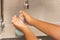 Children cleaning hand with liquid gel in kitchen sink.