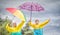 Children with colorful rainbow umbrella,raincoats and waterproof boots jump in the rain