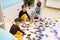 Children connecting jigsaw puzzle pieces in a kids room on floor at home. Fun family activity leisure