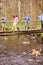 Children Crossing Bridge As Dog Plays In Stream