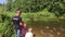 Children with dad feed ducks that swim in the river.