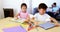 Children doing homework while parents relaxing on sofa