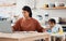 Children, down syndrome and family with a working mother and child in the kitchen of their home. Kids, disability and