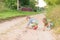 Children draw with a stone on the sand while squatting on a sandy village road