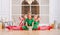 Children dressed in costumes of Christmas elves sitting in twine one after another in front of the mirror in the spacious white