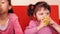 Children eating apples. Two sisters eating yellow apples while sitting on an orange couch.
