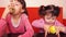 Children eating apples. Two sisters eating yellow apples while sitting on an orange couch.