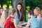 Children and education, young woman at work as educator reading book to boys and girls in park.