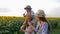 Children enjoy lollipops during walk in the field with sunflowers in straw hats together outdoors