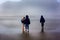 Children Explore Foggy Beach on Wet Sand