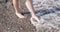 Children feet go along the rocky beach into water