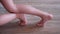 Children feet slide on wooden laminate at home closeup