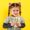 Children and financial responsibility, little girl on a yellow background with dollars in her hands, financial literacy