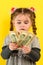 Children and financial responsibility, little girl on a yellow background with dollars in her hands, financial literacy